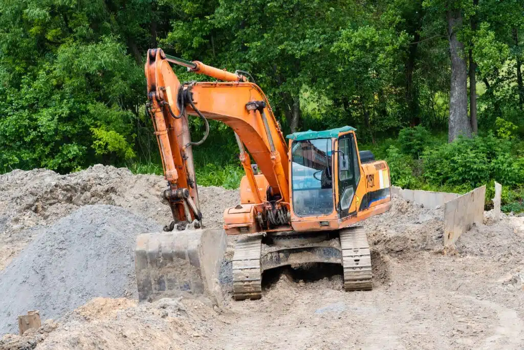 Excavator performs excavation work on the construction site. Yellow tractor digs the ground